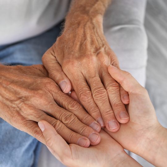 Hands of an
elderly person being held by both hands of a younger
person
