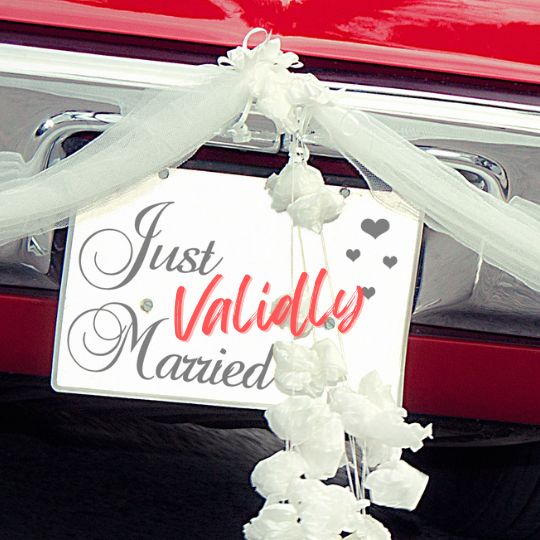 Just
Validly Married Sign on the back of a red
car. Decorated with swathes of cream
tulle, and white flowers