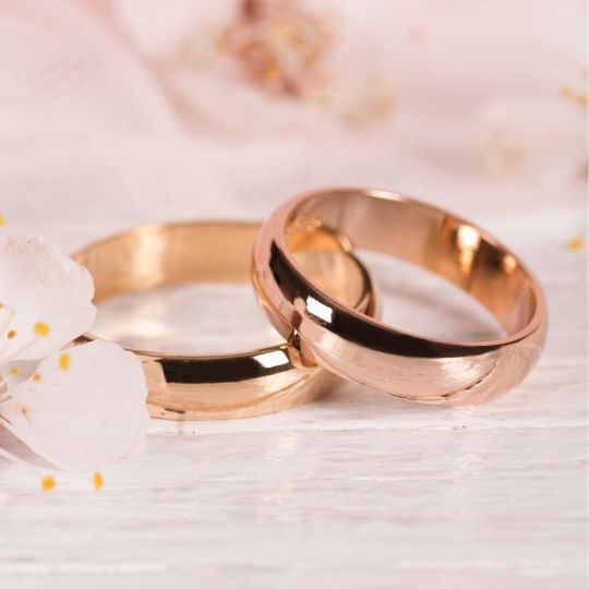 two
gold wedding rings on a pink background