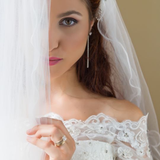 A
bride partially hidden behind a white
curtain